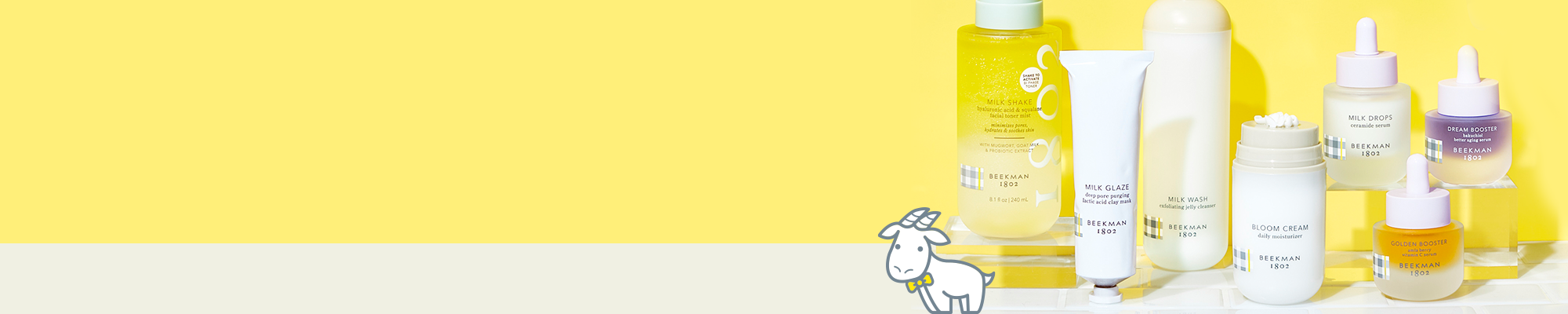 Bottles of Beekman 1802's Clinically Kind Skincare all lined up next to each other on white tile, to the far right of the image on a yellow background, with a cartoon goatie standing next to the bottles.