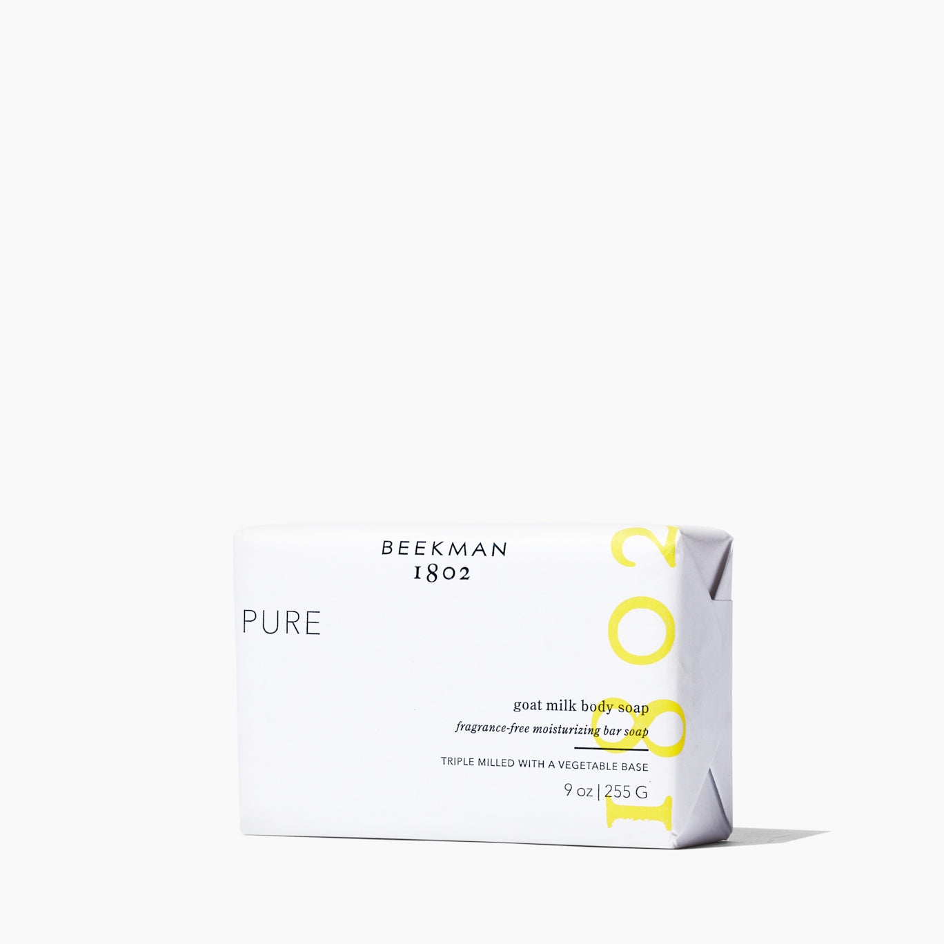 Bar of Beekman 1802's Goat milk pure body soap in white backaging, standing on white background next to shadow.