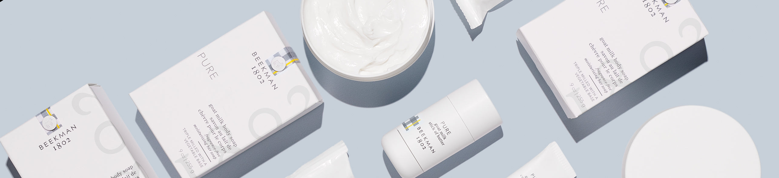Variety of Beekman 1802 products and packaging laying against a grey background