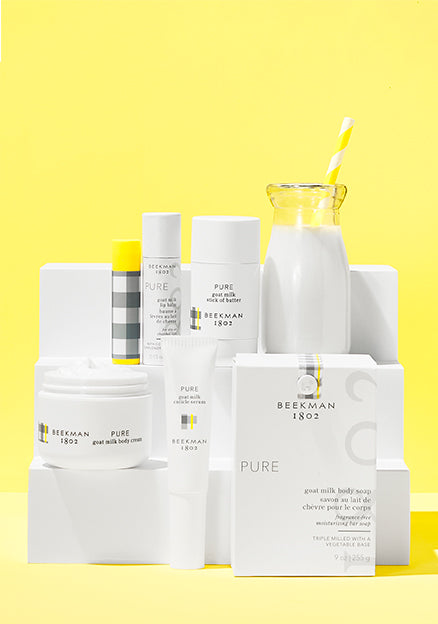 Products from Beekman 1802's Pure Goat Milk Fragrance-Free Bodycare line all displayed next to each other one white acrylic display risers on a yellow background. 