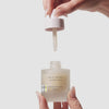 Video of hand holding the beekman 1802 Ceramide milk drops while holding the dropper with the other hand. 